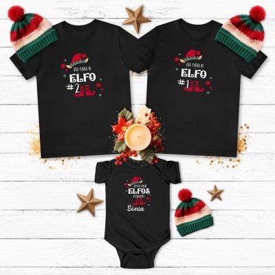 Conjunto de vestuário preto com estampados natalícios e chapéus de malha coloridos, sobre fundo de madeira branca.