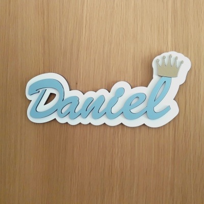 Nome em madeira com a palavra Daniel em azul claro e coroa dourada