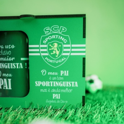 Caixa e caneca verdes SCP Sporting Portugal com texto em branco sobre relva artificial