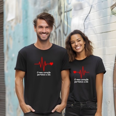 Casal sorridente com t-shirts pretas estampadas com corações e linhas de eletrocardiograma, em ambiente urbano com graffiti
