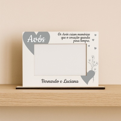 Moldura de fotografia branca com texto e detalhes cinzentos, apoiada sobre mesa de madeira clara
