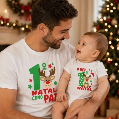 Pai e bebé com camisolas de Natal brancas com estampados verdes, vermelhos e uma rena, em ambiente natalício.