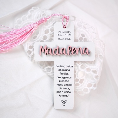 Cruz branca com nome Madalena em rosa e tassel rosa sobre fundo branco com renda