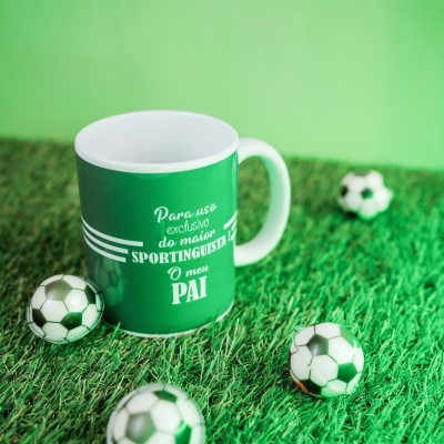 Caneca verde com texto e bolas de futebol sobre relva artificial