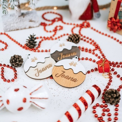 Enfeites de Natal em madeira personalizados com nome, decorados com neve falsa e bolas vermelhas.