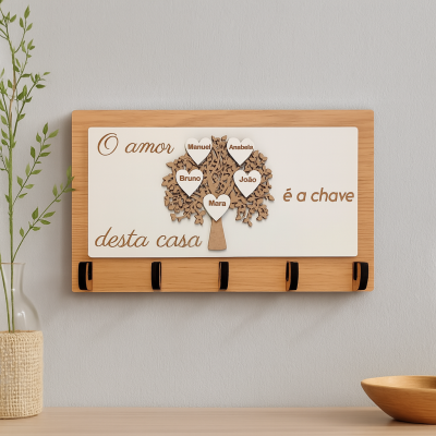Suporte de chaves de madeira com decoração de árvore e corações com nomes, frase em português e cinco ganchos pretos na parede cinza