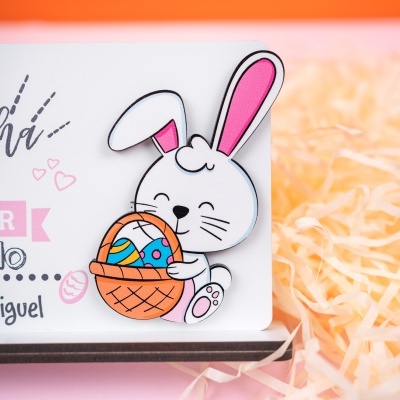 Cartão branco com desenho de coelho segurando cesta com ovos coloridos