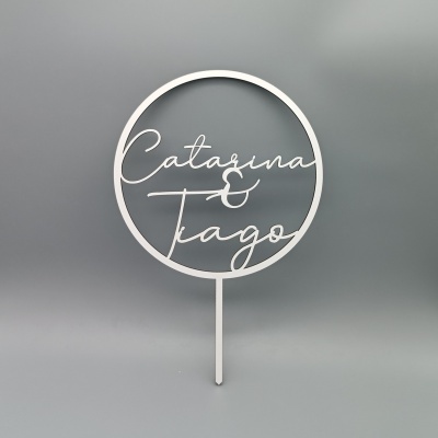 Topo de bolo branco com nomes Catarina & Tiago em fundo cinzento.