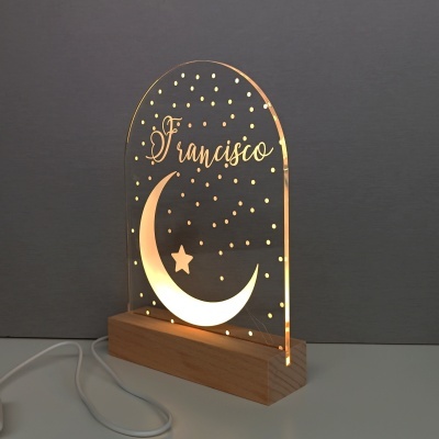 Lâmpada decorativa com design de lua e estrela em acrílico iluminado sobre base de madeira