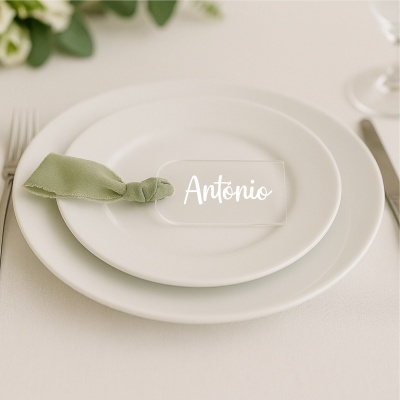 Mesa posta com pratos brancos, guardanapo verde e marcador de mesa com o nome António.
