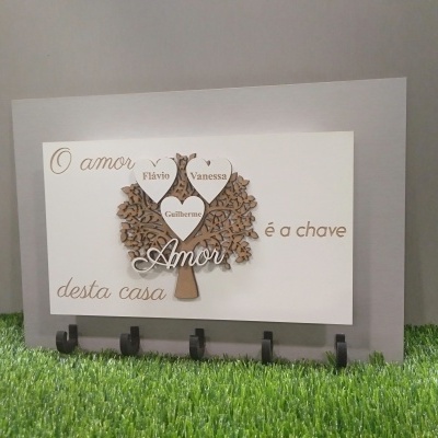 Quadro decorativo cinza com árvore, corações com nomes e ganchos pretos.