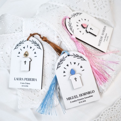 Marcadores de livros brancos com vela de madeira e tassel coloridos sobre tecido branco rendado