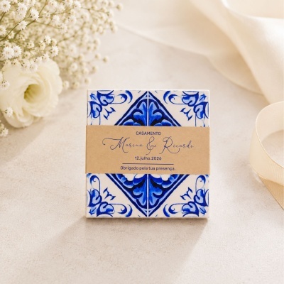 Caixa cerâmica azul e branca com etiqueta de casamento sobre fundo claro com flores e tecido.
