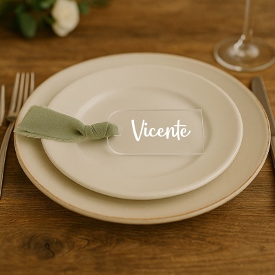 Etiqueta transparente para mesa com o nome Vicente em pratos brancos e guardanapo verde numa mesa de madeira