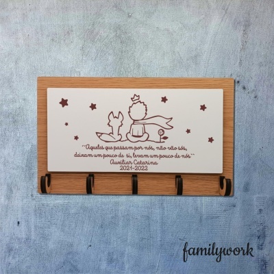 Cabideiro de madeira com placa branca decorativa e texto em português, apoiado em fundo cinzento.