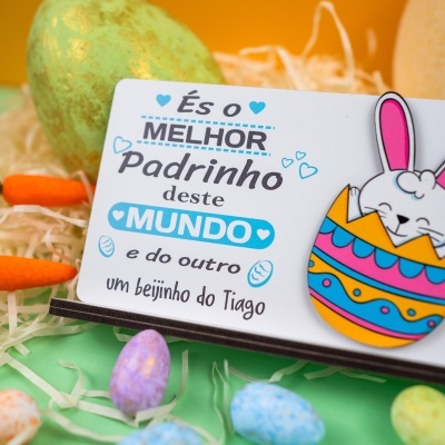 Cartão com mensagem para padrinho e ilustração de coelho colorido com ovos decorativos em fundo laranja e verde