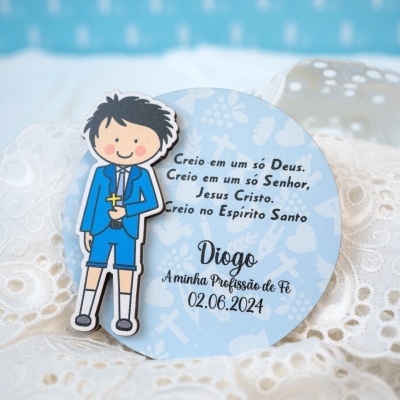Cartão redondo azul claro com figura de menino em roupa azul e texto em português com nome Diogo e data.
