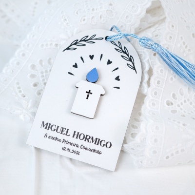 Marcador de madeira com vela e cordão azul sobre tecido branco bordado