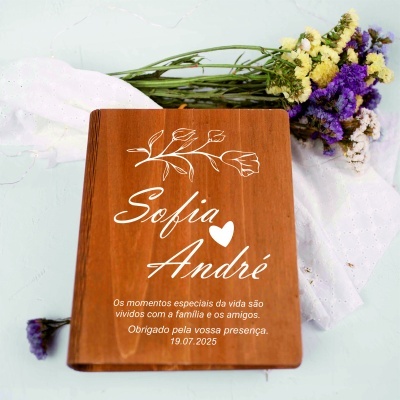 Livro de madeira com texto branco, flores secas e tecido branco de fundo