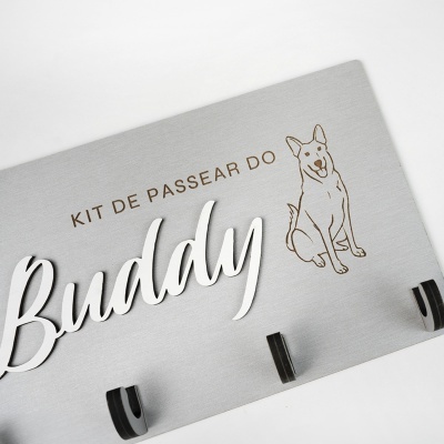 Placa cinza com texto KIT DE PASSEAR DO Buddy e desenho de um cão e ganchos pretos