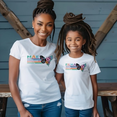 Duas mulheres a sorrir de t-shirts brancas com design colorido sobre mãe e filha, com borboleta e flores, numa sala com parede azul e detalhes em madeira.