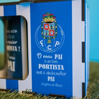 Caixa azul e branca com brasão e texto FCP sobre relva artificial