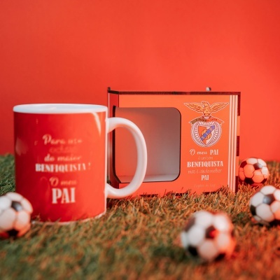 Caneca vermelha e branca com caixa e mini bolas de futebol sobre relva artificial