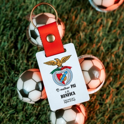 Chaveiro com presilha vermelha e cartão com brasão do SL Benfica sobre bolas de futebol em relva