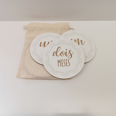 Placas redondas de cartão branco com texto em dourado e saco de tecido cru