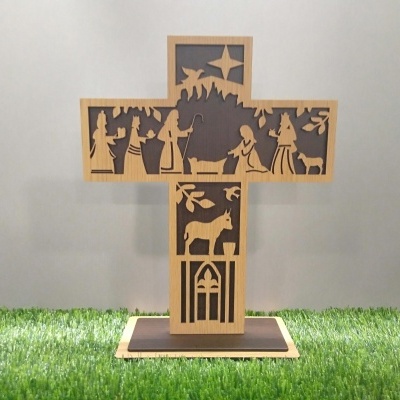 Cruz de madeira com recortes da Natividade sobre base em relva artificial
