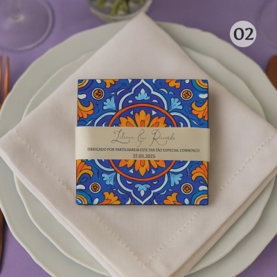 Convite colorido azul e laranja com texto em fita bege num conjunto de pratos e guardanapo branco em fundo lilás