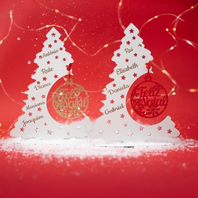 Enfeites de Natal em forma de árvore com nomes e bolas Feliz Natal penduradas sobre fundo vermelho com luzes