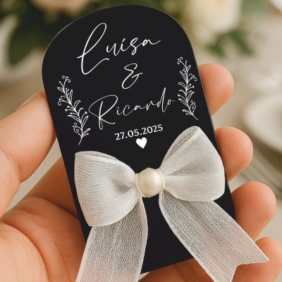 Etiqueta preta com laço branco e texto decorativo de casamento Luisa & Ricardo 27.05.2025