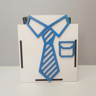 Suporte branco em forma de camisa com gravata azul e canetas no topo