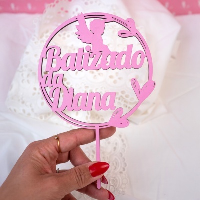 Topo de bolo cor-de-rosa com texto Batizado da Diana e desenho de anjo