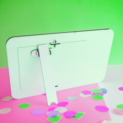 Dispositivo branco com suporte em superfície rosa com confetes coloridos