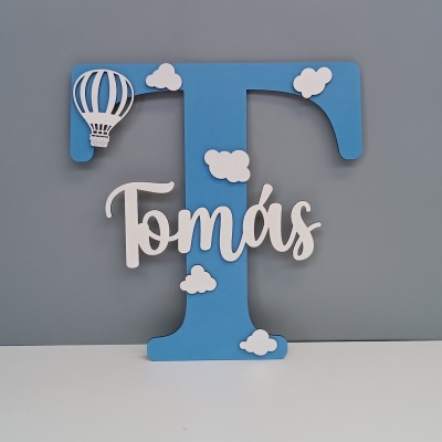Letra decorativa em madeira azul com nome Tomás, nuvens brancas e balão de ar quente