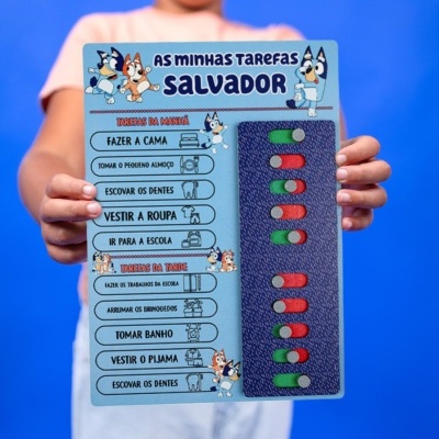 Quadro infantil de tarefas com botões deslizantes e ilustrações coloridas, segurado por uma criança