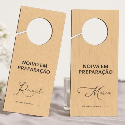 Duas placas penduradoras de porta em madeira clara com texto em preto para noivos em preparação.
