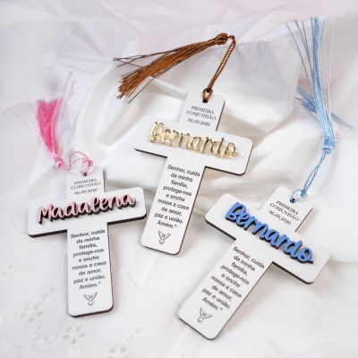 Cruzes de madeira com nomes em relevo e tassels coloridos sobre tecido branco