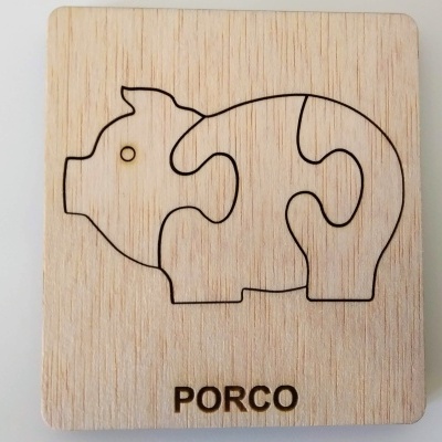 Peça de madeira com puzzle em forma de porco e palavra PORCO gravada