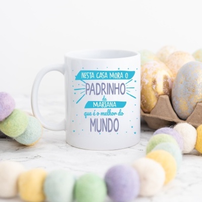 Caneca branca com texto personalizado sobre padrinho rodeada de decoração colorida