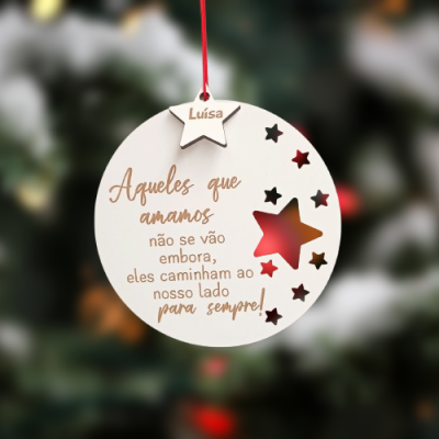 Ornamento de Natal redondo branco com estrelas e texto em português pendurado numa árvore