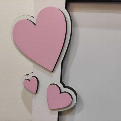Moldura branca com corações cor-de-rosa em madeira com contorno preto