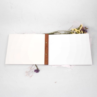 Livro aberto com encadernação de couro castanha e flores secas ao redor