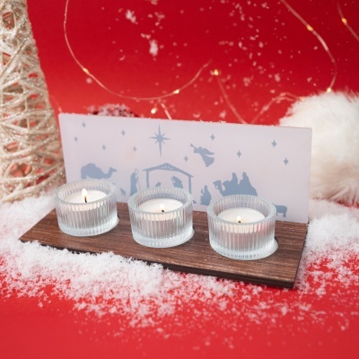 Conjunto de velas em vidro com decoração natalícia em fundo vermelho.