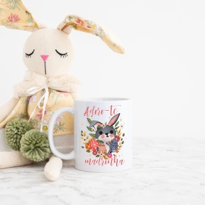 Caneca branca com coelho e texto Adoro-te madrinha ao lado de coelho de pano vestido floral
