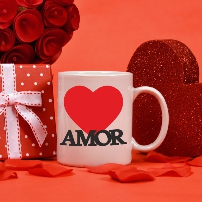 Caneca branca com coração vermelho e texto AMOR, caixa de presente vermelha com bolinhas brancas e laço, corações vermelhos brilhantes e flores sobre fundo laranja