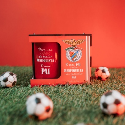 Copo vermelho e embalagem vermelha com emblema do SL Benfica e texto, bolas de futebol na relva