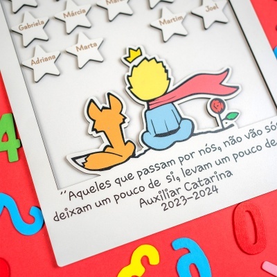 Quadro branco com estrelas de nomes e ilustração colorida do Pequeno Príncipe com raposa, texto em português e fundo vermelho com letras coloridas.